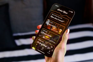 Hand holding up a mobile phone which displays the Amber Hour App